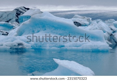 Serene and majestic water in the form of large icebergs floating away from the calving face of the glacier