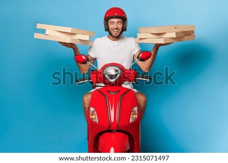 Delivery guy on red scooter against blue backdrop, wearing red helmet, holding pizza boxes in both hands, delivery service concept, copy space Royalty-Free Stock Photo #2315071497