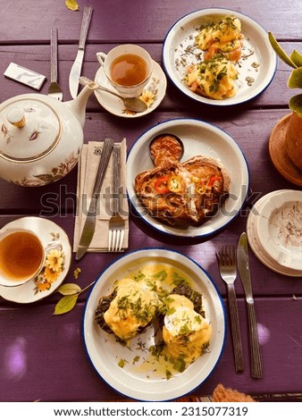 Artistic Brunch Delights: Cozy Setting with Vintage Tableware on a Purple Table, Bathed in Sun Rays Royalty-Free Stock Photo #2315077319