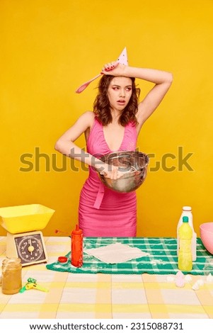 Young pretty birthday girl in dress and bright makeup cooking cake and feeling tired against vivid yellow background. Concept of party, celebration, emotions, female beauty, youth. Pop art