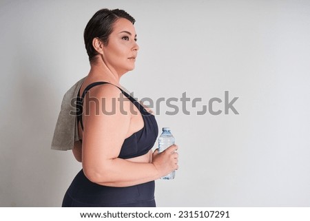 Portrait of happy plus size woman holding water bottle