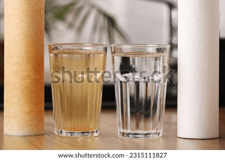 House water filtration system to drinkable condition. New clean water filter cartridge and glass of clear water. Used cartridge in rust and glass of dirty water on tabletop kitchen. World aqua day Royalty-Free Stock Photo #2315111827