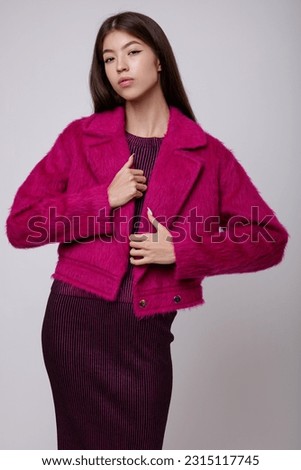 Fashion photo of a beautiful elegant young asian woman in a pretty pink fuchsia dress, jacket posing on white, soft gray background. Studio Shot, portrait. Slim figure. 