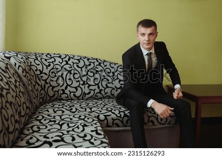 portrait. A man in a white shirt and gray pants is sitting on a sofa next to elegant red men's shoes. A stylish watch. Men's style. Fashion. Business