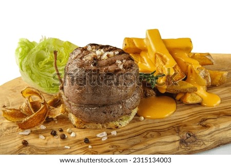 Beef filet mignon steak  with fried potatoes and cheese sauce.Grilled beef tenderloin steak on a wooden board
