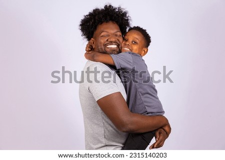 Portrait of handsome young black father and his cute son hugging tightly and happily