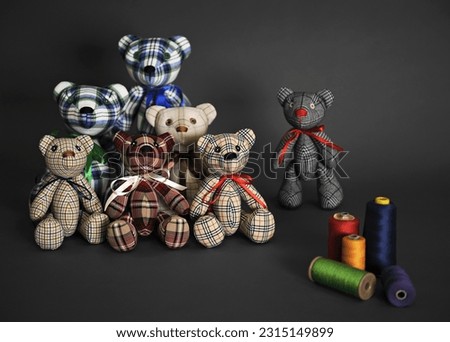 Teddy bears. Children's handmade soft toys. Sewn bears in cage. Several bears and threads on dark gray surface. Front view. Dark gray background. High quality photo Royalty-Free Stock Photo #2315149899