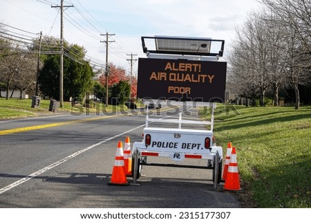Electronic traffic alert sign by a road that says, "Alert Air Quality Poor" Royalty-Free Stock Photo #2315177307