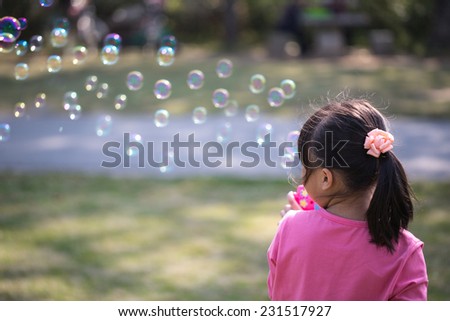 Little girl blowing bubbles under the sun