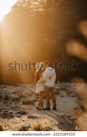 Close-up of boho couple in nature holding hands and walking, hugging having fun for their engagement photo session.