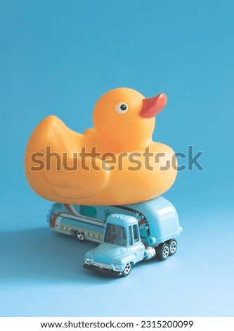 Toy retro caravan car with rubber duck on a blue background. Concept of family summer vacation and travel by trailer. Minimalistic summer retro composition with children's toys. Close-up