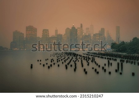Long exposure photography of lower Manhattan, New York, covered in wildfire smoke from Canada.  Viewed from Brooklyn.