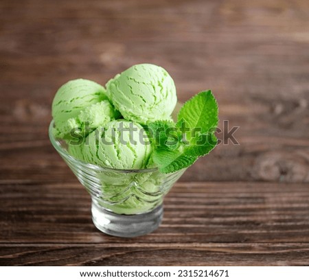 Pistachio ice cream in a transparent cup close-up with mint leaves on a wooden table