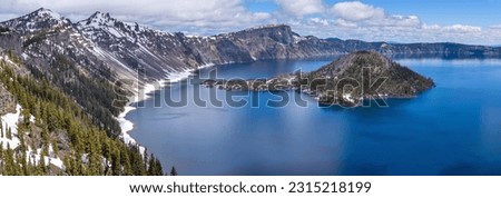 Wizard Island - A Spring day panoramic view of Wizard Island, surrounded by deep blue water of Crater Lake and rugged lake rim. Crater Lake National Park, Oregon, USA.