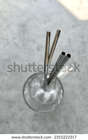 reusable stainless steel straws and cleaning brush in gray bag on gray background, eco friendly lifestyle