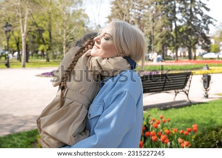 Mother and daughter having fun in the park. Happy family concept. Beauty nature scene with family outdoor lifestyle. Happy family resting together. Happiness and harmony in family life.