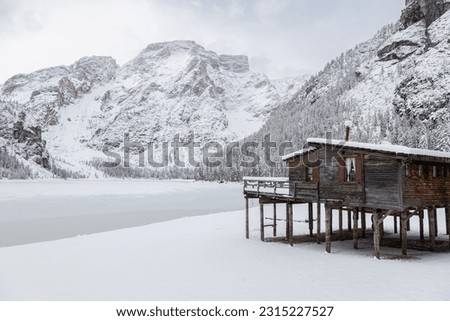 View of a wooden hut and Braies Lake completely frozen in a snowy winter day; Dolomites; Alto-Adige, Italy Royalty-Free Stock Photo #2315227527