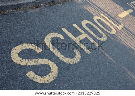 Yellow road marking "School" UK painted on an asphalt road