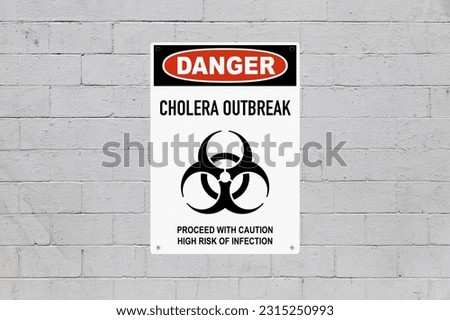 Warning sign screwed to a cinder block wall  with a biohazard symbol and the message is saying "Danger, cholera outbreak. Proceed with caution, high risk of infection". Royalty-Free Stock Photo #2315250993