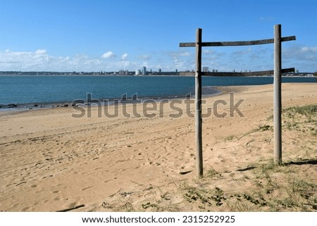 Photography of a beautiful beach with a placid ocean and the skyline of Punta del Este behind