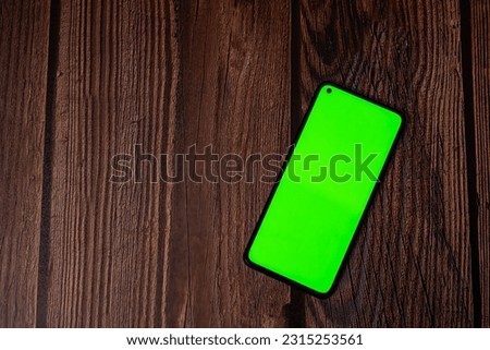 A photo of a mobile phone with a green chromakey screen.