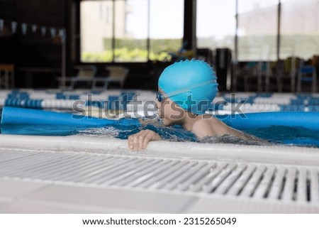Close up boy swimmer o school boy learning how to swim in a pool wearing in swimming cap and goggles Royalty-Free Stock Photo #2315265049