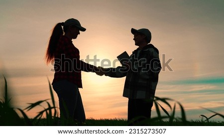 Two farmers conclude contract in wheat field. Handshake for signing contract. Agricultural industry using digital technologies.Concept of agricultural business. Using computer tablet in agribusiness