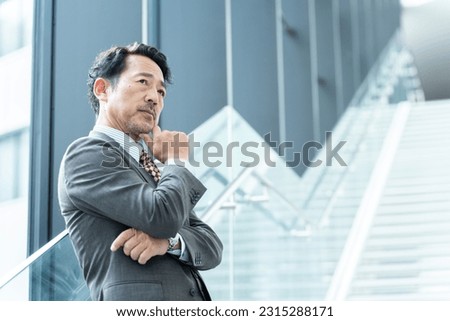 Middle-aged Asian businessman thinking in office Royalty-Free Stock Photo #2315288171