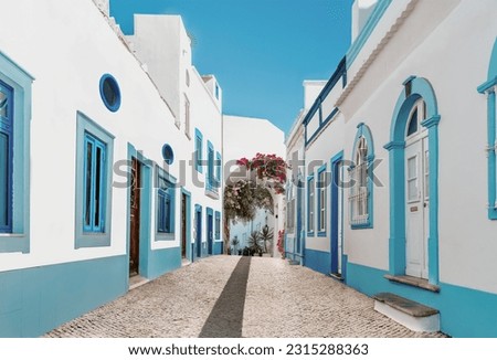 Street in fishermen village with white and blue houses and typical Portuguese pavement in Olhao, Algarve region - Popular travel destinations in Portugal Royalty-Free Stock Photo #2315288363