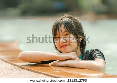 Portrait ofAsian teenage cute girl looking at camera in swimming pool