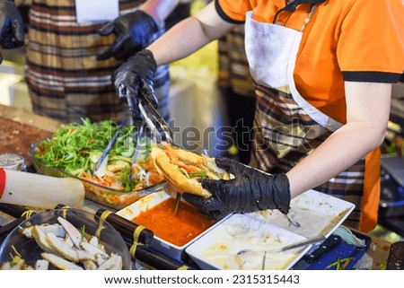 Vietnamese woman serving traditional vietnamese sandwich banh mi in street food at night Royalty-Free Stock Photo #2315315443