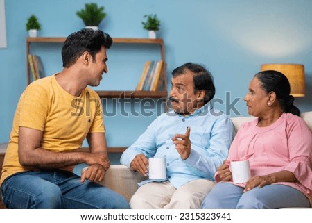 Indian happy adult son with senior parents talking or discussing together at home - concept of family communication, discussion and sharing thoughts. Royalty-Free Stock Photo #2315323941