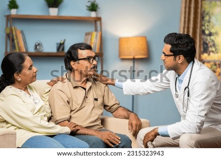 Indian doctor consoling senior couple by giving confidence while sitting on sofa at home - concept of mental illness, health care support and assistance Royalty-Free Stock Photo #2315323943