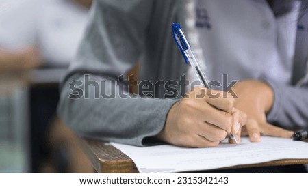 The students were doing the exams inside the classroom with stress.Assessment examination of high school students dressed in uniform Royalty-Free Stock Photo #2315342143