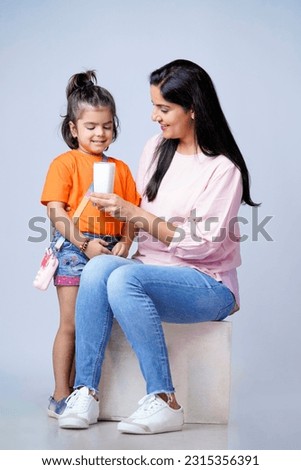 Indian mother giving milk in glass his daughter on white background. Royalty-Free Stock Photo #2315356391