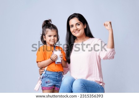 Indian mother giving milk in glass his daughter on white background. Royalty-Free Stock Photo #2315356393