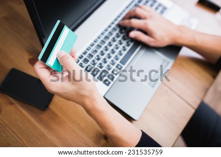 Man holding a credit card and typing. On-line shopping on the internet using a laptop  Royalty-Free Stock Photo #231535759