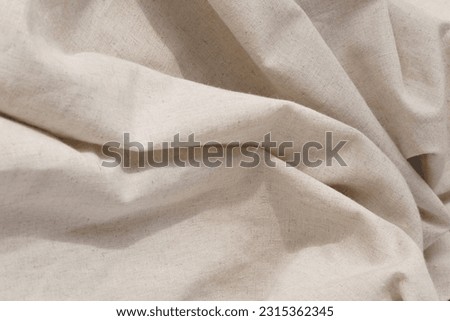 Soft draped neutral beige linen fabric texture, aesthetic textile background with an abstract folds, wedding or brand template, copy space