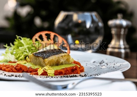 Fried cod fillet with vegetables and mashed potatoes is on a plate.