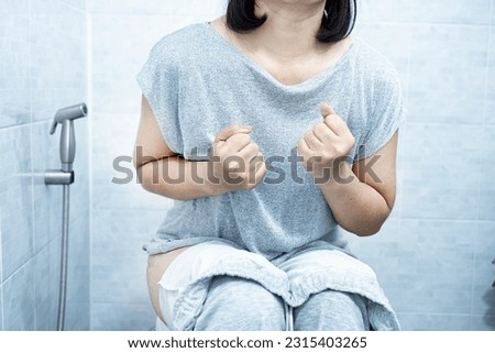 woman have problem with chronic constipation, bowel movement is painful sitting in toilet  Royalty-Free Stock Photo #2315403265