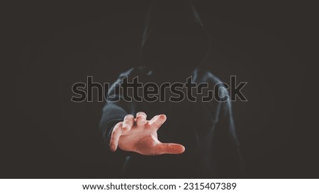 Hacker, Criminal, thief wearing hood reaches his hand to picking up or steal valuable things or assets from victims. Internet security, threat, ransomware or phishing concept. Royalty-Free Stock Photo #2315407389