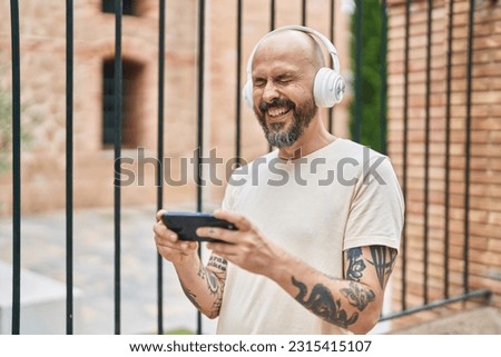 Young bald man smiling confident watching video on smartphone at street