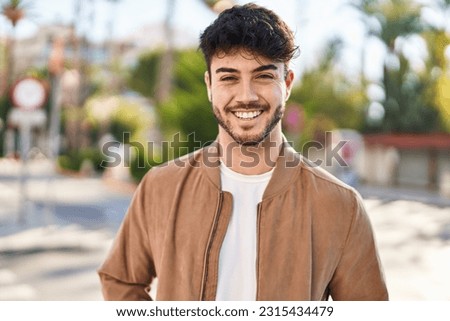 Young hispanic man smiling confident standing at street Royalty-Free Stock Photo #2315434479