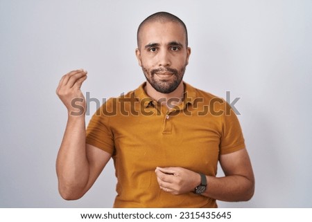Hispanic man with beard standing over white background doing italian gesture with hand and fingers confident expression 