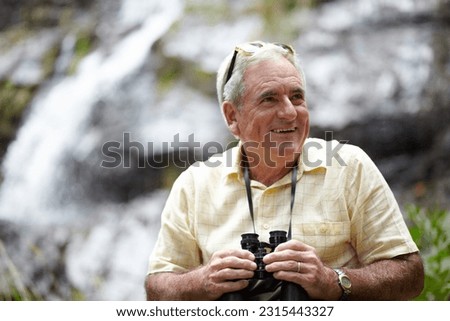 Binoculars, happy man and forest or mountains thinking of journey, outdoor adventure and carbon footprint tourism. Senior person with gear for birdwatching experience or search nature by waterfall Royalty-Free Stock Photo #2315443327