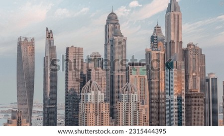 Skyscrapers of Dubai Marina with illuminated highest residential buildings night to day transition . Aerial top view from JLT district before sunrise