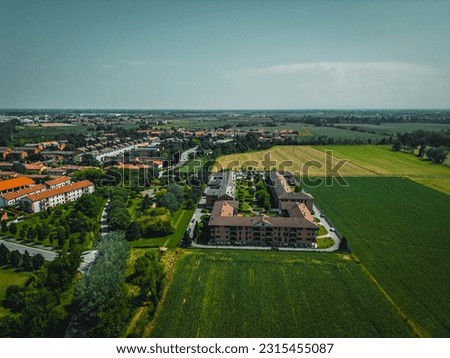Amazing drone view of fields and farmland with small villages on the horizon. Summer rural terrain landscape. Lombardy, Italy.