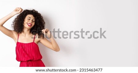 Happy elegant woman in red dress dancing on white studio background.