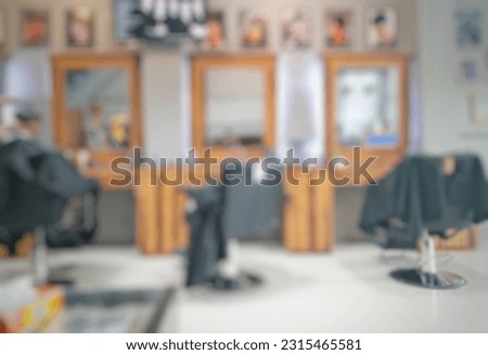 The back view of a handsome hairdresser cutting a male client's hair. The hairdresser serves the clients at the barber shop. Blur background