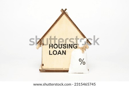 A picture of wooden house written housing loan with interest percentage sign money bag on white background